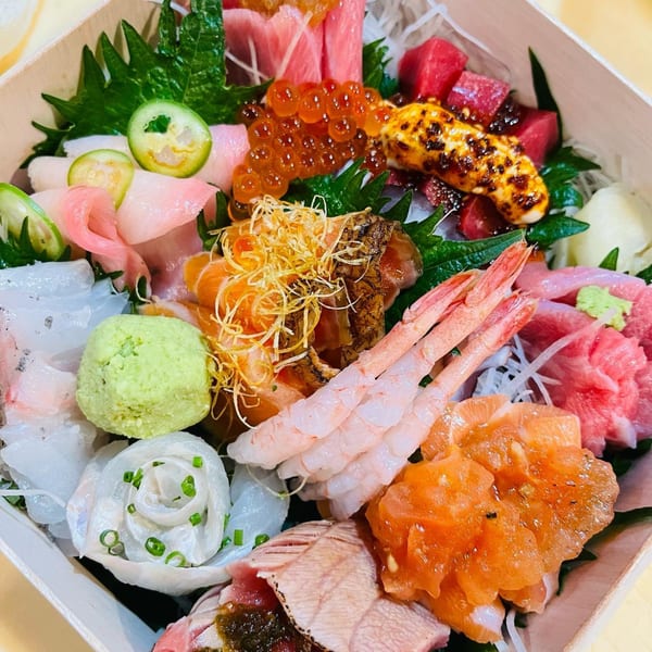 A vibrant Sushi Hatsune chirashi bowl with various sashimi, roe, shrimp, and wasabi.